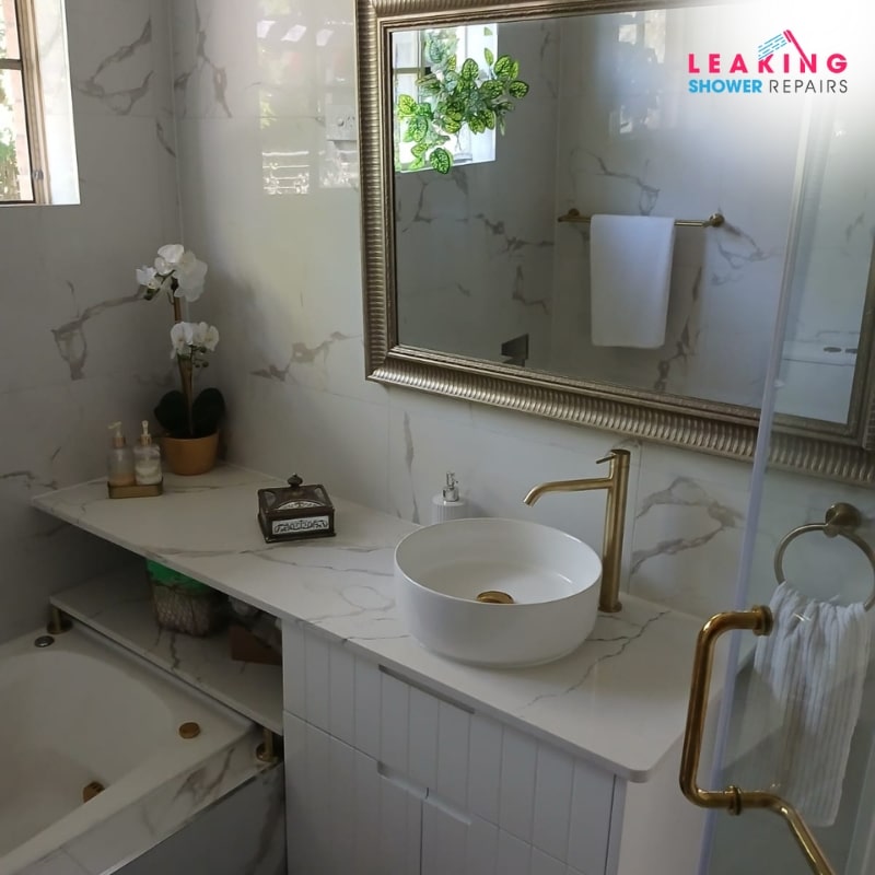 Reliable bathroom renovation services: A stylish bathroom with marble tiles, gold fixtures, and a freestanding tub.