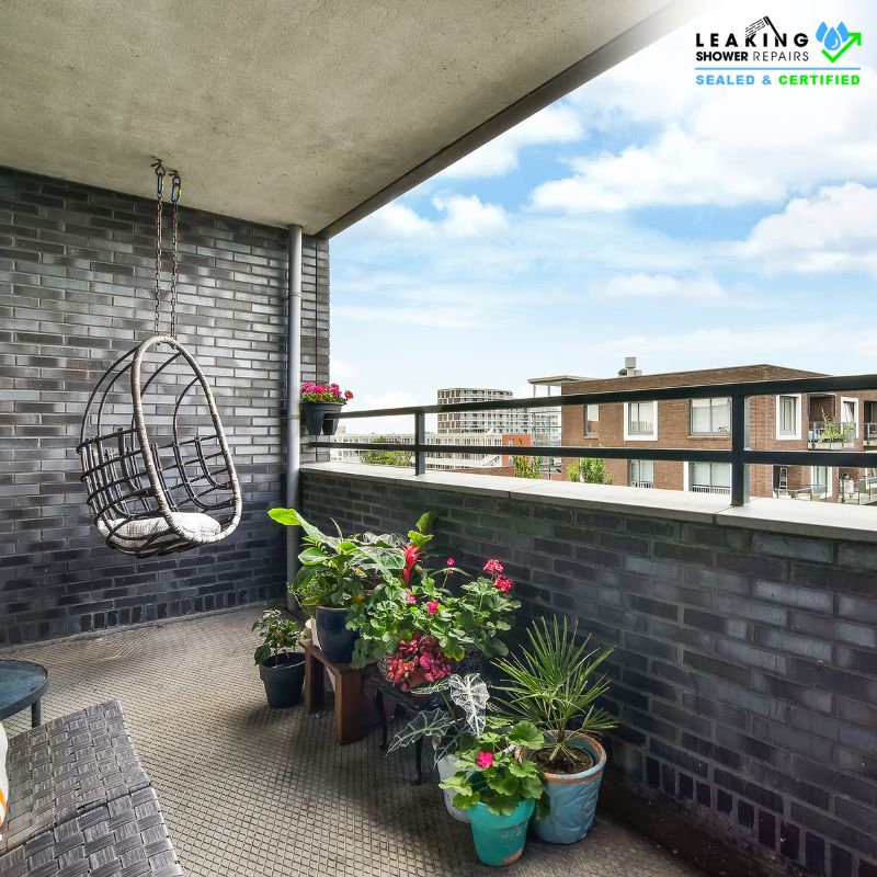 Cosy balcony with hanging chair, potted plants, and dark brick walls needing waterproofing.