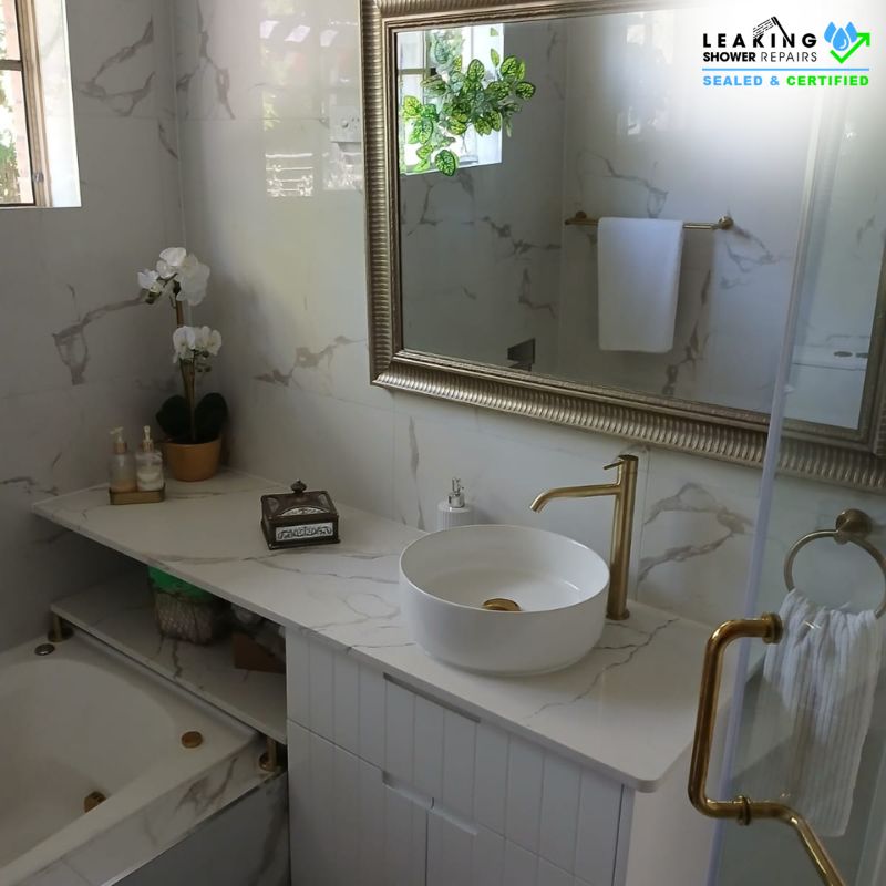 Reliable bathroom renovation services: A stylish bathroom with marble tiles, gold fixtures, and a freestanding tub.